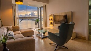 A modern living room with a sofa, a glass coffee table, a TV, and a view of the sea. - 23 A Espacioso Apto en Yoo con Vista Mar 2 Rec (Panamá)