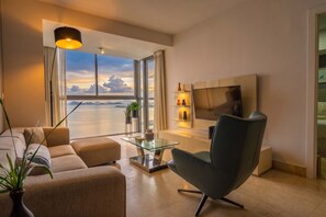 A modern living room with a sofa, a glass coffee table, a TV, and a view of the sea. - 23 A Espacioso Apto en Yoo con Vista Mar 2 Rec (Panamá)