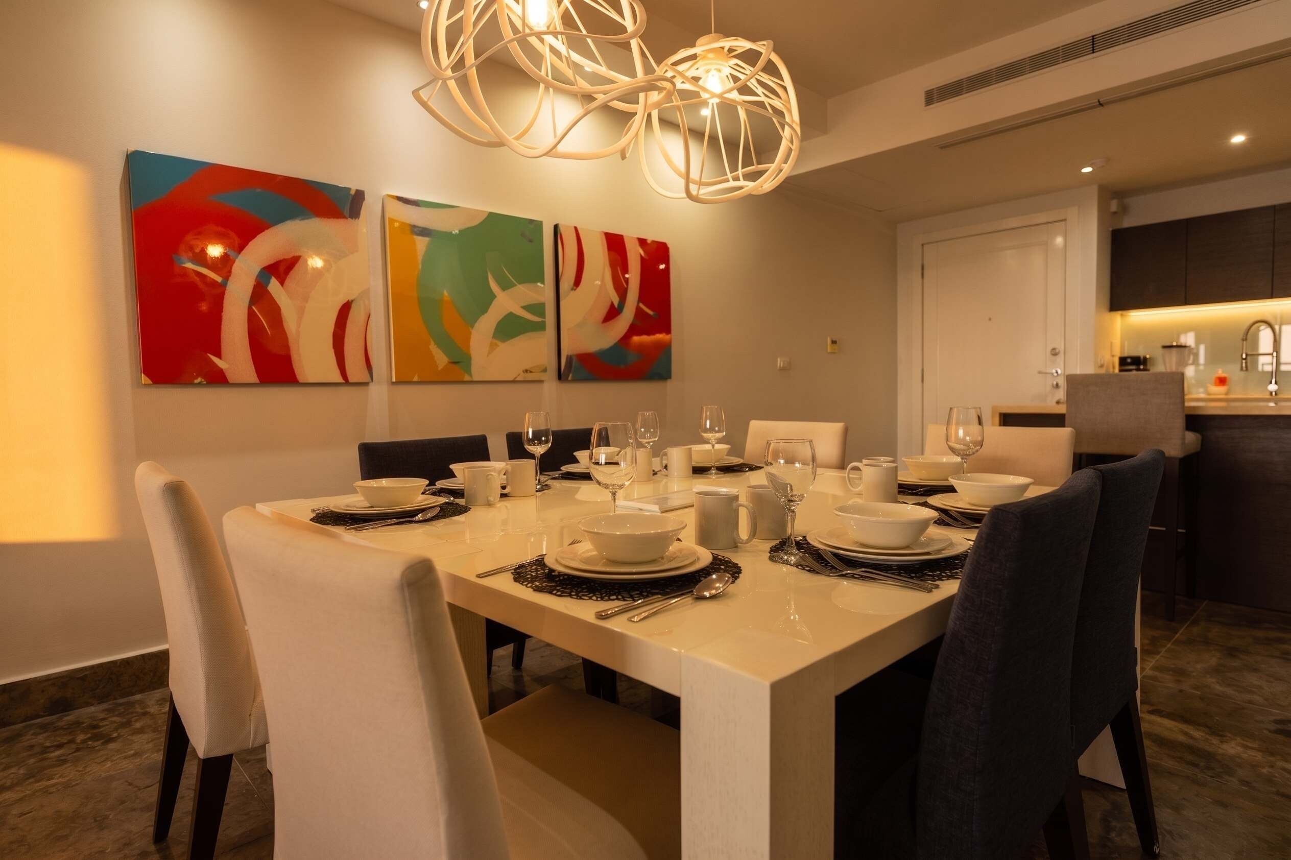 A dining area with a table set for four, chairs, and abstract wall art.