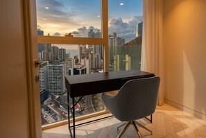A modern office space with a large window overlooking a cityscape, a desk, and an office chair. - 24G Apto en Wanders & Yoo Marbella con 3 recamaras (Panama City)