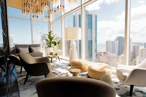 Ein modernes Wohnzimmer mit Blick auf die Stadt, großen Fenstern und zeitgemäßen Möbeln.
