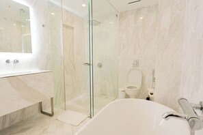 Un bagno moderno con doccia a vetro, una vasca freestanding e un piano di marmo.