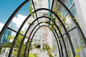 Ein modernes Gebäude mit Glasfassade, einem zentralen Atrium mit Pflanzen und Blick auf eine Stadtlandschaft.