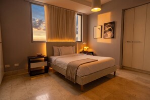 Ein Schlafzimmer mit einem Bett, Nachttischen, einem fenster mit Vorhängen, einer Wandlampe und einem Kleiderschrank.
