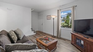 Una sala de estar con un sofá, una mesa de centro, un televisor y una lámpara.