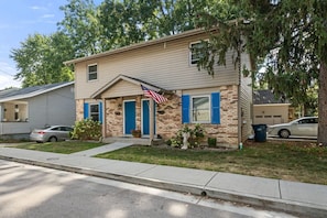 A single-story house with a front porch, a small garden, and a garage. - Townhouse on Perry - Walk to Main Street (Saint Charles)