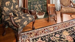 A living room with a fireplace, patterned armchairs, a wooden floor, and a floral rug. - Oma’s Haus - Walk to Main Street! (Saint Charles)