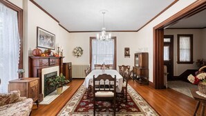 A dining room with a fireplace, wooden furniture, a chandelier, and a floral rug. - Oma’s Haus - Walk to Main Street! (Saint Charles)
