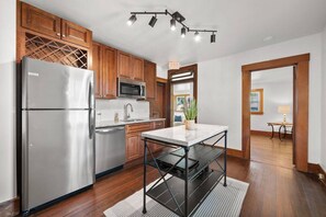 A modern kitchen with stainless steel appliances, wooden cabinets, and a central island. - The Barker Bungalow - Charming 3 bedroom in Historic Town near shops and dining (Saint Charles)