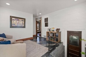 A living room with a sofa, a rug, and a painting on the wall. - The Barker Bungalow - Charming 3 bedroom in Historic Town near shops and dining (Saint Charles)