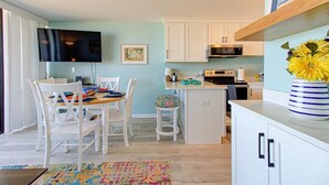 Cocina compacta con armarios blancos, microondas y una pequeña isla.
