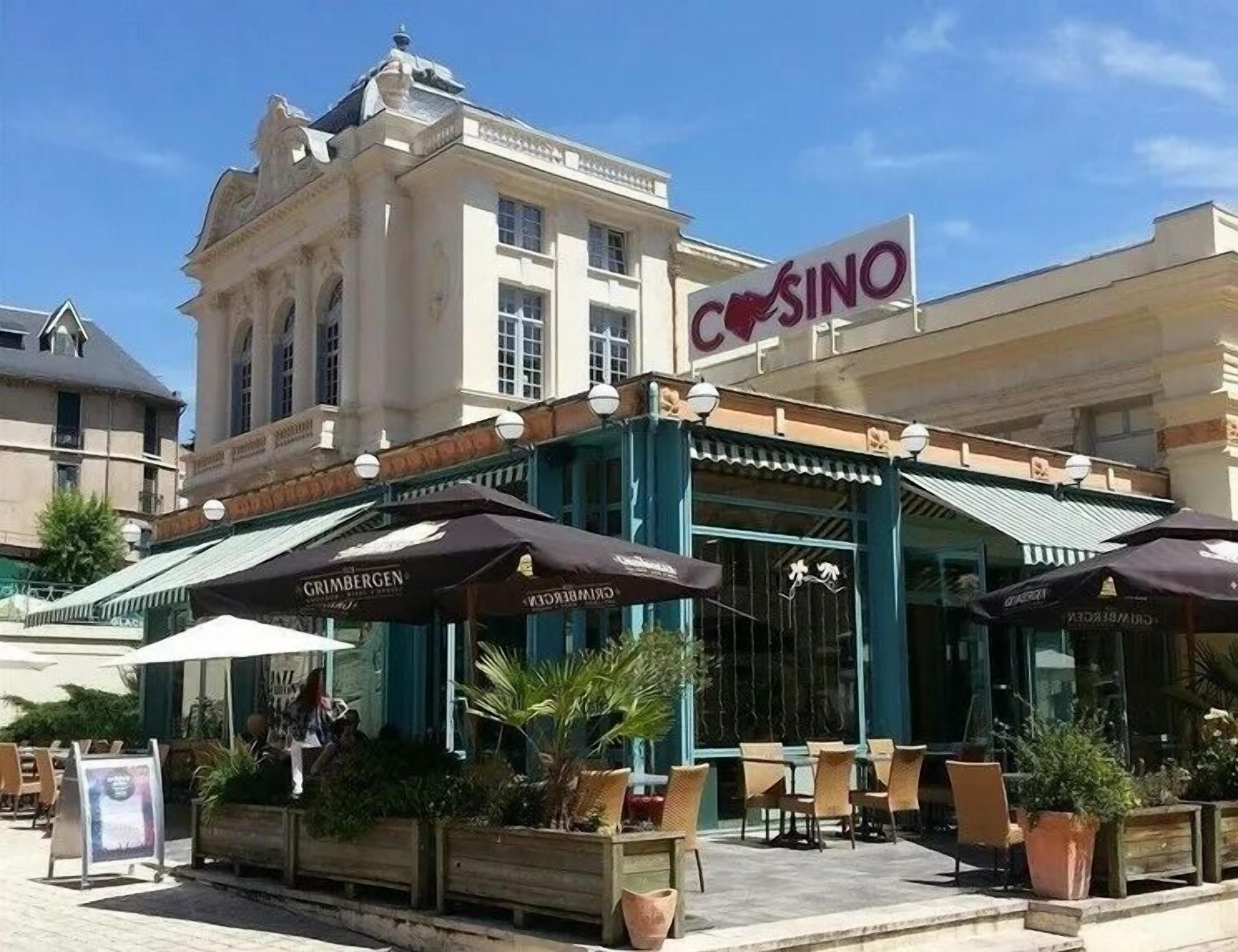 Un edificio con un letrero que dice 'COSINO' y terraza al aire libre con sombrillas.