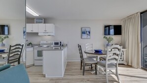 Una cucina moderna con mobili bianchi, un forno a microonde e un'area pranzo con tavolo e sedie.