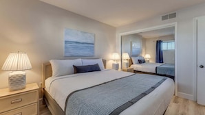 Una camera d'albergo con un letto grande, lampade sui comodini, un comodino, uno specchio e un quadro appeso al muro.