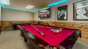 A pool table with a red felt surface, pool cues, and balls, a bench, and framed pictures on the wall. - Porchside Pines։ Private Hot Tub (Pigeon Forge)