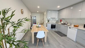 Une cuisine moderne avec des meubles blancs, une table à manger en bois et une plante en pot.