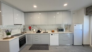 Une cuisine moderne avec des meubles blancs, un four à micro-ondes, un lave-vaisselle et un évier.