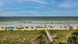 A beach with umbrellas, a boardwalk, and the ocean. - Charming 1 Bedroom Oceanfront Condo in Carolina Beach, perfect for 6 guests 0409 (Carolina Beach)