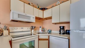 A kitchen with a microwave, stove, dishwasher, and sink. - Experience oceanfront luxury at 0411 Seaside Sunrise, Carolina Beach! (Carolina Beach)