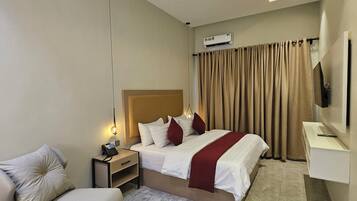 Una habitación de hotel moderna con una cama, mesita de noche, lámpara y televisor de pantalla plana.
