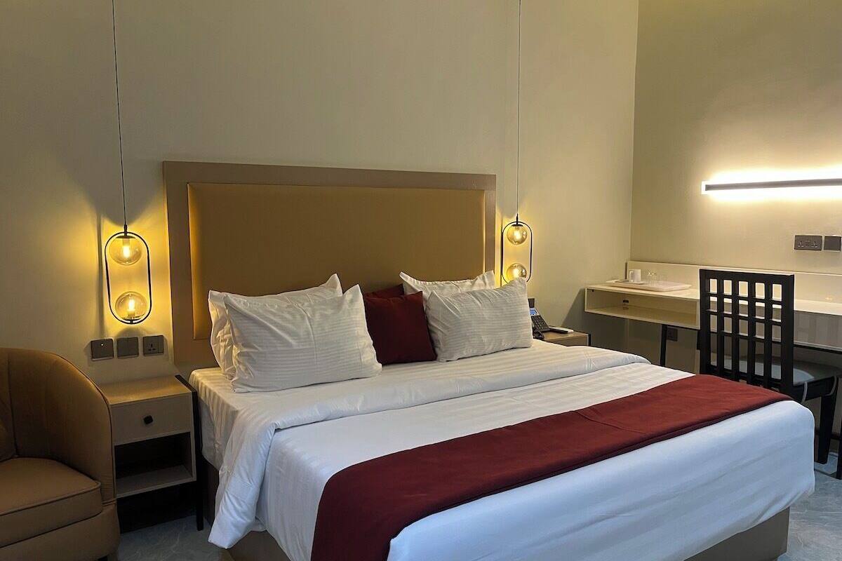 Ett hotellrum med en säng, sängbord, ett skrivbord och en stol.