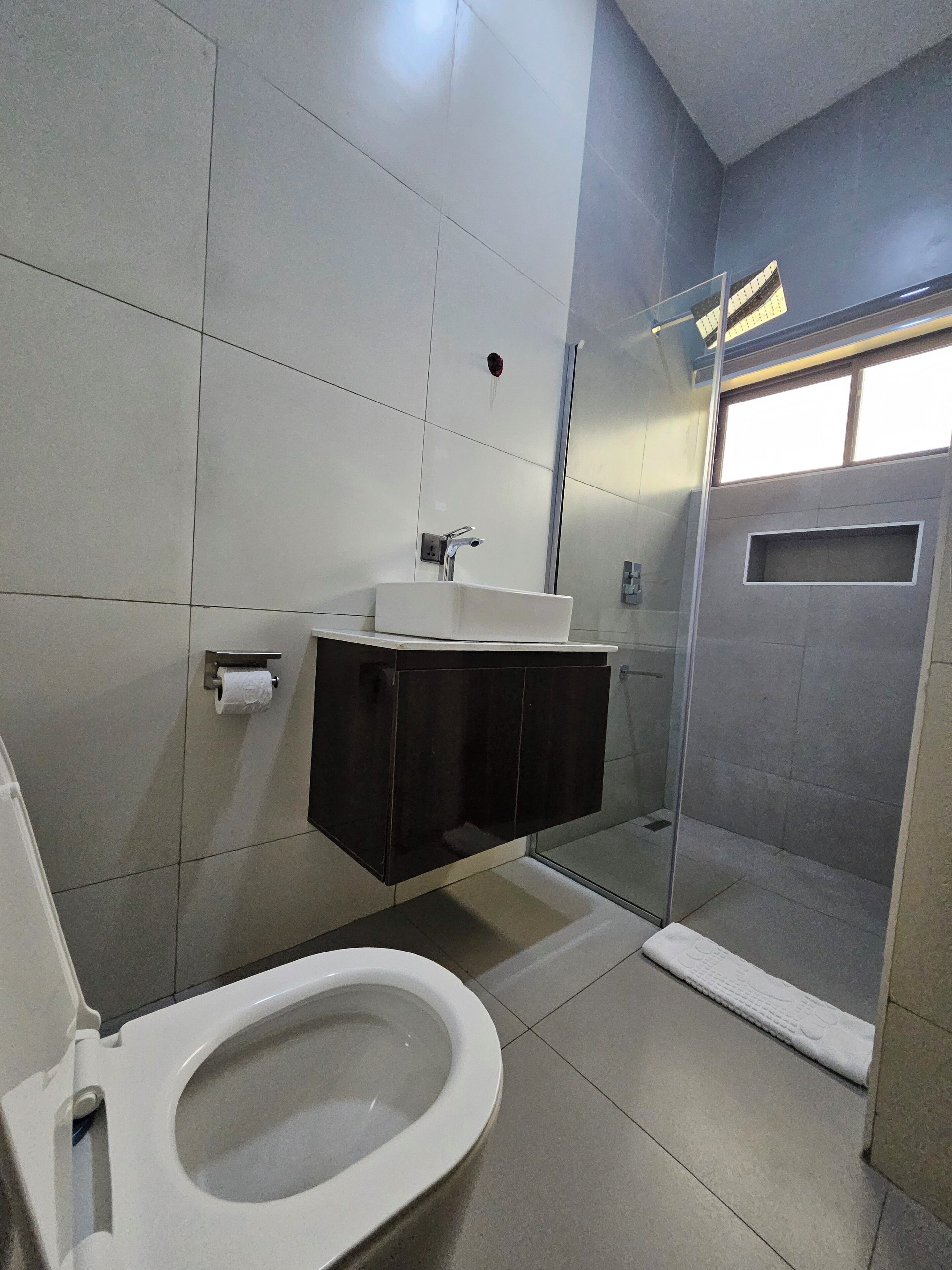 Une salle de bain moderne équipée de toilettes, d’un lavabo et d’un espace douche.