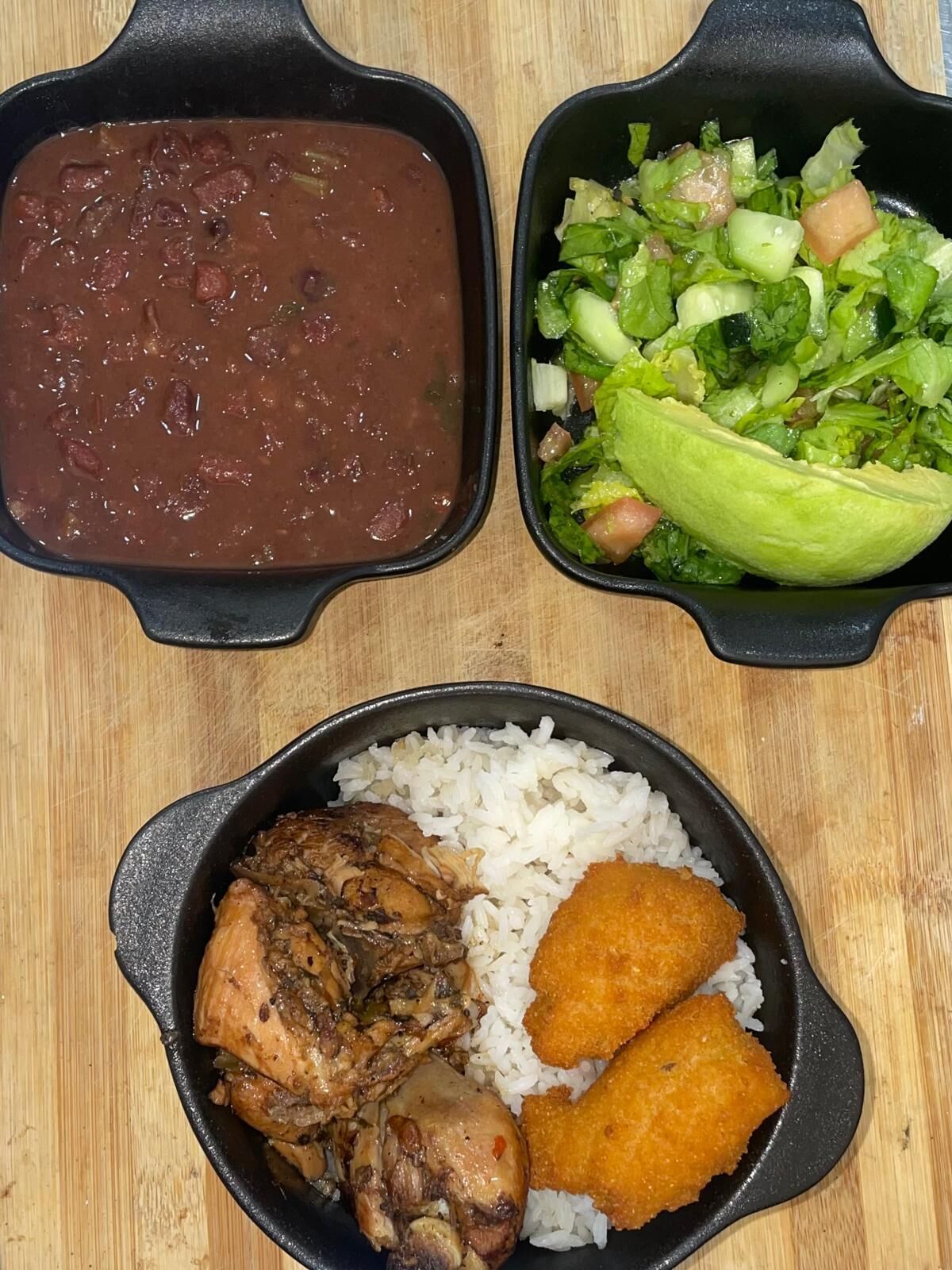 A meal with rice, chicken, and fried items, along with a bowl of beans and a salad.