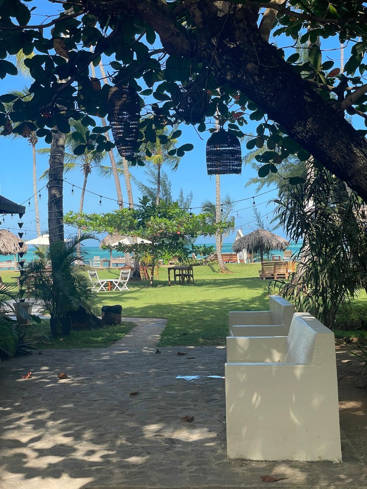 Un recurs tropical amb una cabana de palla, palmeres i una vista nítida de l'oceà.