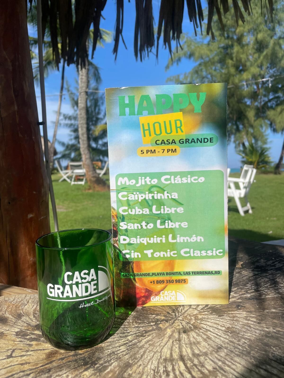 A menu board for Casa Grande with a green glass labeled 'CASA GRANDE' on a wooden surface.