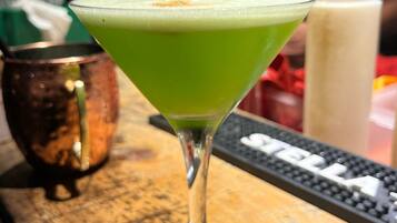 Een barsetting met een groene cocktail in een martini-glas, een koperen beker en een toetsenbord op de achtergrond.