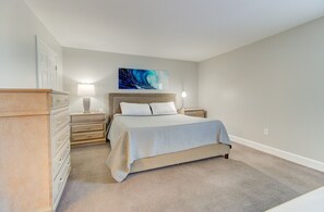 Un dormitorio con cama, mesitas de noche, cómoda y un cuadro en la pared.