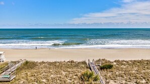 Una spiaggia con una passerella di legno che conduce all'acqua, una torretta di salvataggio e un cielo sereno.