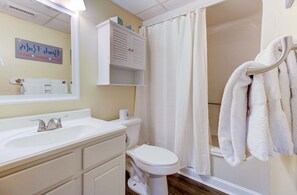 A bathroom with a sink, toilet, and shower curtain. - Oceanfront condo in Carolina Beach, perfect for a relaxing getaway 0607 (Carolina Beach)