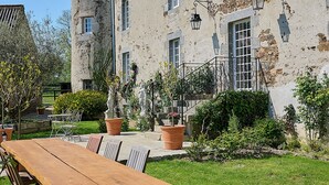 A stone building with a tower, a wooden table, and potted plants in the yard. - Charming manor house in Brittany (Binic-Étables-sur-Mer)