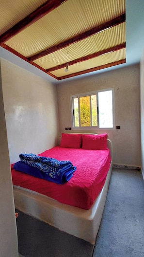 A room with a bed, a window, and a ceiling fan.