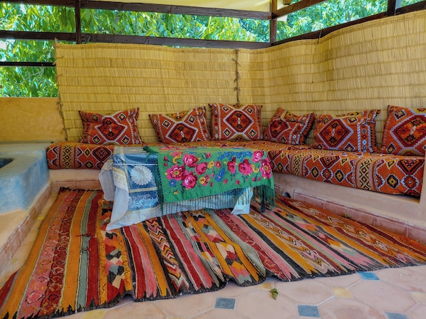Una habitación con un conjunto de sofá, una mesa con mantel de flores y una alfombra estampada.