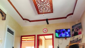 Quarto com televisão, espelho, tapete estampado e lareira tradicional.