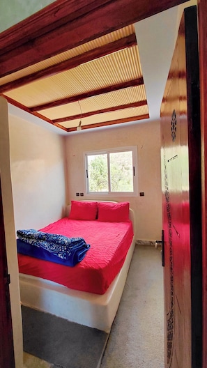 A room with a bed, a window, and a door.