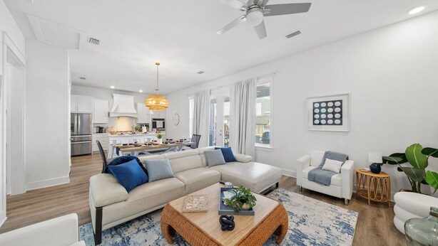 A modern living room with a sofa, coffee table, and a dining area with a kitchen in the background. - Pet friendly, walk to the beach, Master Swim Spa & Firepit -Villas of Frangista (Miramar Beach)