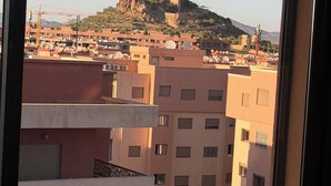 Vista de un paisaje urbano con una colina destacada al fondo, edificios residenciales con balcones y un cielo despejado.