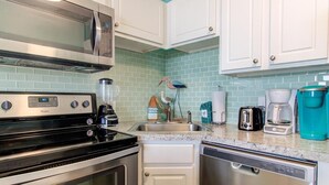 A kitchen with a microwave, stove, dishwasher, and a coffee maker. - Seaside serenity awaits at 0609 Oceanfront Escape in Carolina Beach! (Carolina Beach)