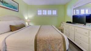 A bedroom with a bed, dresser, television, and a window. - Seaside serenity awaits at 0609 Oceanfront Escape in Carolina Beach! (Carolina Beach)