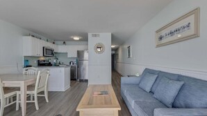 A modern apartment with a kitchen, dining area, and living room. - Seaside serenity awaits at 0609 Oceanfront Escape in Carolina Beach! (Carolina Beach)