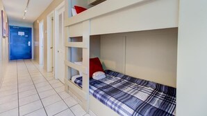 A room with bunk beds, a blue door, and a tiled floor. - Breathtaking oceanfront views await at 0610 Smooth Sailing in Carolina Beach. (Carolina Beach)