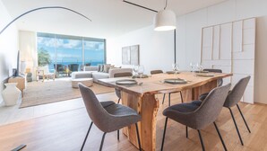 Ein stilvoller Essbereich mit einem Holztisch, grauen Stühlen und einem großen Fenster mit Blick ins Freie.