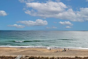 A beach with a clear sky, calm sea, and a few people. - Enjoy oceanfront views at 0701 The Green Starfish, a cozy 1-bedroom retreat in Carolina Beach. (Carolina Beach)
