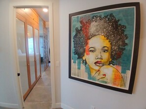 Un couloir avec un tableau accroché au mur et une porte donnant sur une autre pièce.