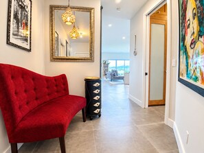 A hallway with a red sofa, a mirror, and a view to the outside.
