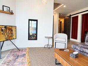 Una sala de estar moderna con un cuadro grande, una fotografía enmarcada, un sofá, una mesa de centro y una alfombra estampada.