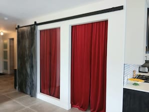 A room with a sliding door, a kitchen area with a gas stove, and a tiled floor.